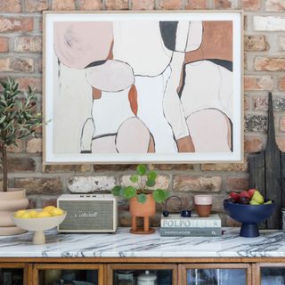 side board with decorative objects, artwork and exposed brick wall