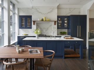 A navy shaker style kitchen with white marble slab walls