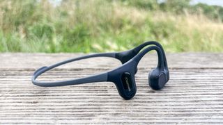 Mojawa Run Plus bone-conduction headphones on wooden bench outdoors 
