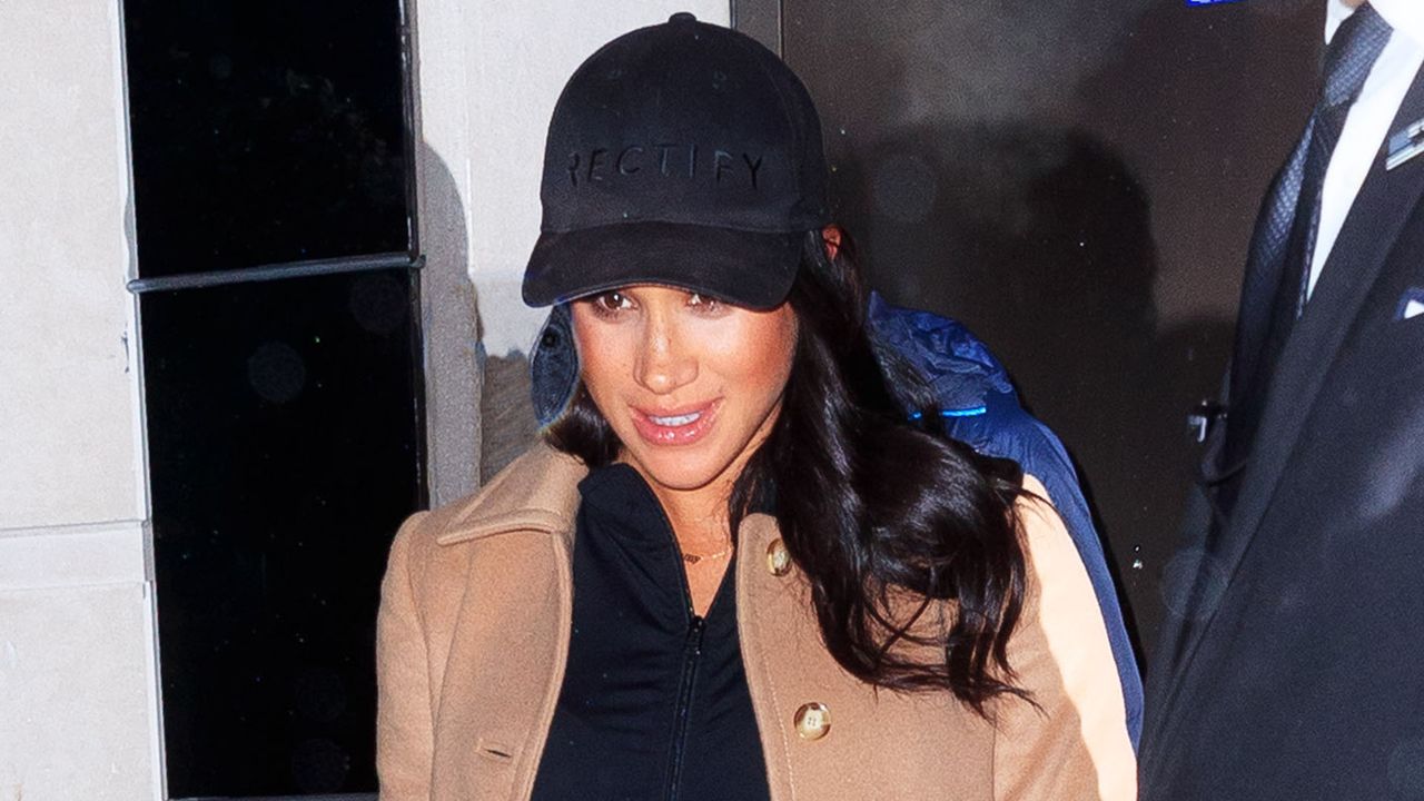 Meghan Markle wearing a tan overcoat and dark baseball cap while out in New York City in 2019.