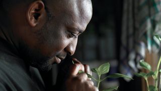 A man smelling plants in a garden