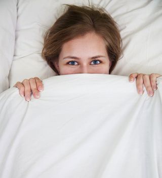 A woman in bed under the covers.