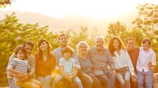 Portrait of happy multi-generation family sitting on garden wall. 