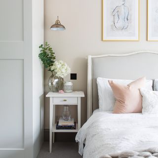 Pale pink bedroom with white linens, upholstered headboard and art above bed