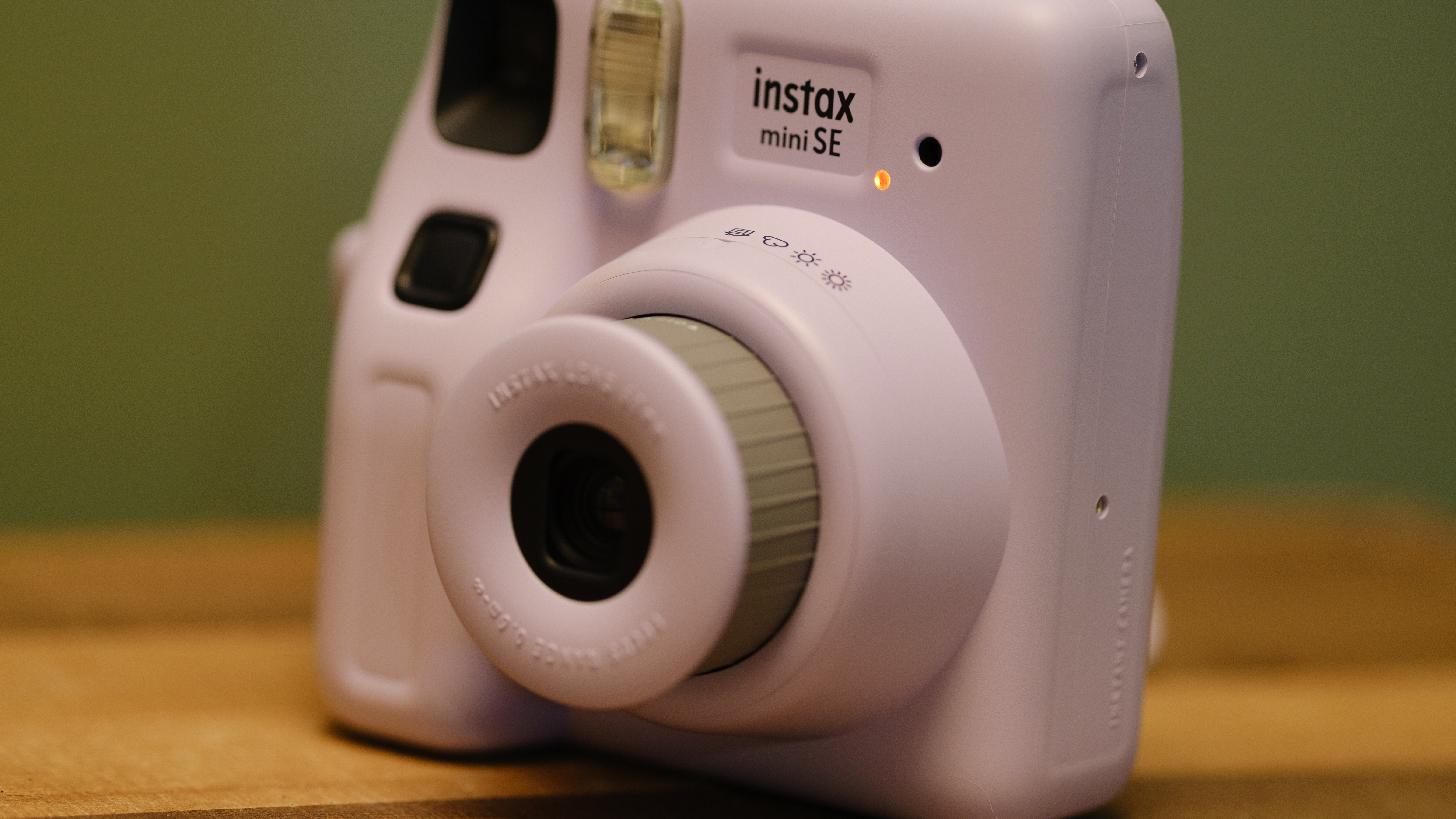 The Fujifilm Instax Mini SE sits on a table powered on