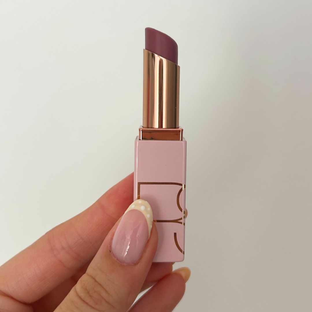 Hand holding tube of NARS Afterglow Lip Balm