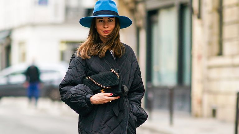 PARIS, FRANCE - OCTOBER 08: Therese Hellström wears a blue hat from Bronte, a black quilted Chanel bag with golden chain, a black padded puffer long coat from Custommade, blue denim Custommade jeans, black pointy Custommade shoes, on October 08, 2020 in Paris, France. (Photo by Edward Berthelot/Getty Images)