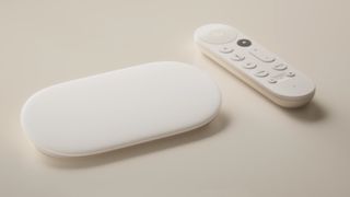 The Google TV Streamer box on a couch next to its remote control