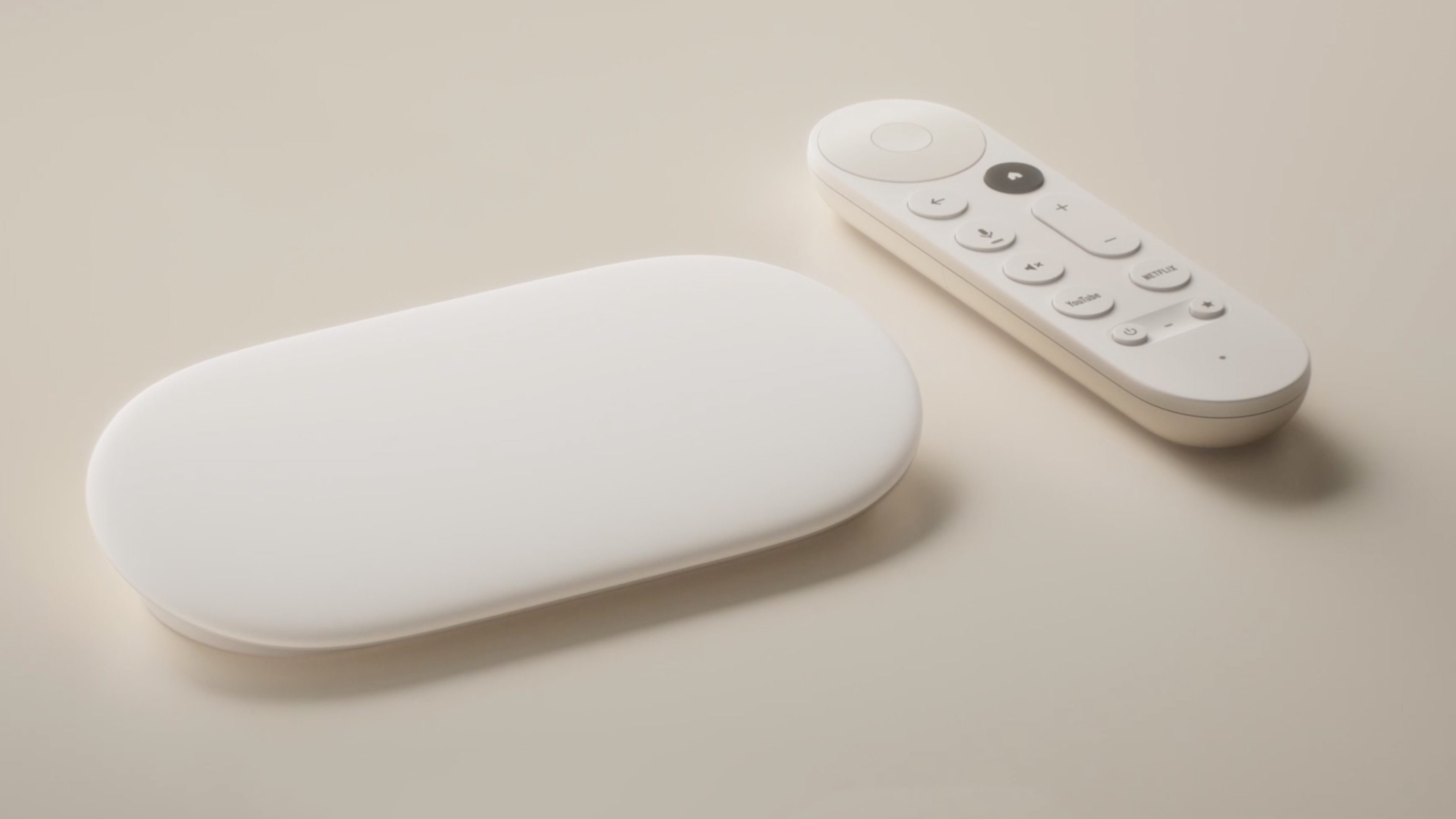 The Google TV streamer box on a sofa next to its remote control