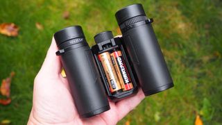 Nikon Stabilized 12x25 S binoculars held in a hand showing the batteries in their compartment