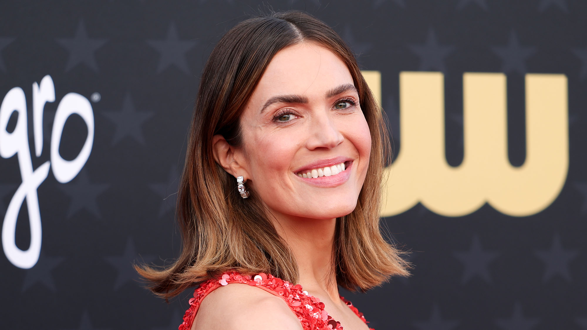 Mandy Moore wearing a red dress in front of black background at The 29th Critics' Choice Awards