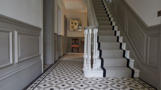 hallway with patterned tile floor and original staircase with runner