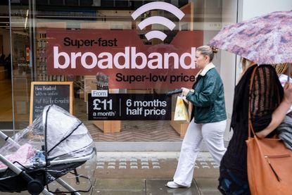 A fibre broadband offer in a shop window with people walking past (image: Mike Kemp/In Pictures via Getty Images))