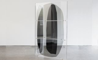 A see-through art piece has multiple layers connected together. It's displayed on glass.