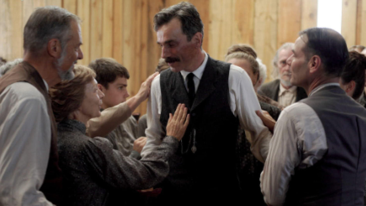 Daniel Day-Lewis as Daniel Plainview surrounded by people in There Will Be Blood.
