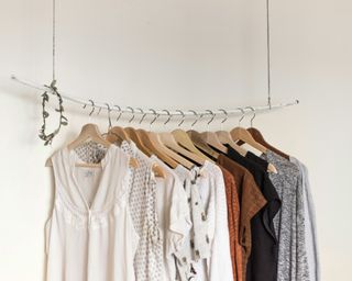 a minimalist style wardrobe rail - a single white rail with items of a neutral color palette hanging from it