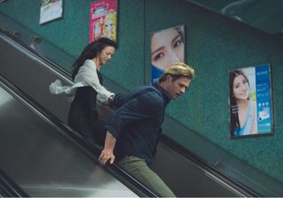 Wei Tang and Chris Hemsworth run down an escalator