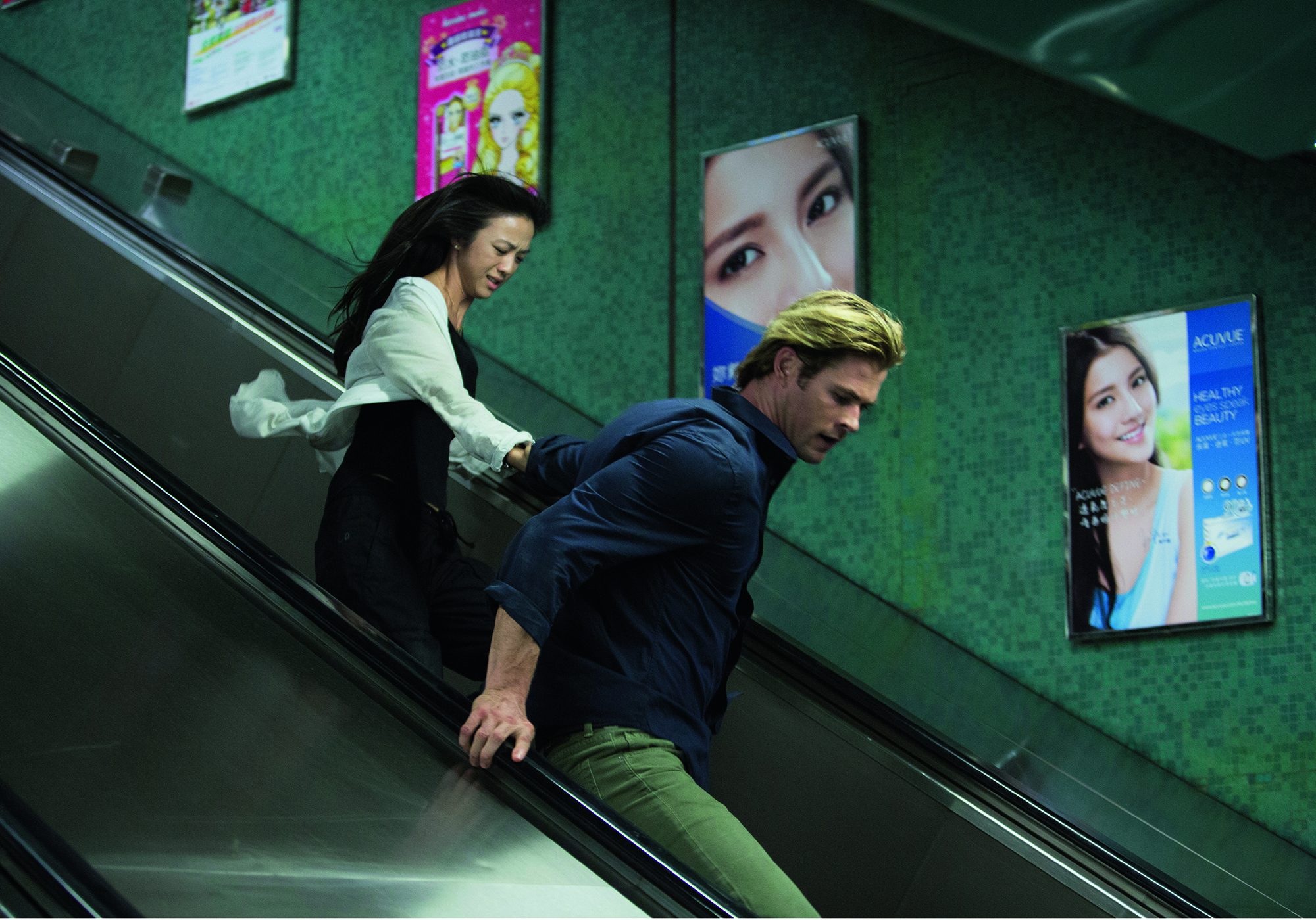 Wei Tang and Chris Hemsworth run down an escalator