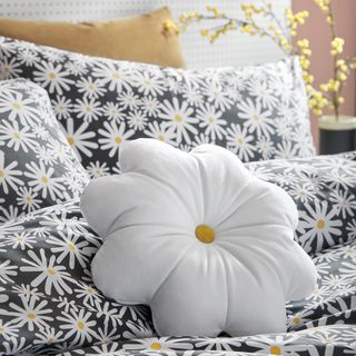 room with white daisy pillow and daisy print bedsheet