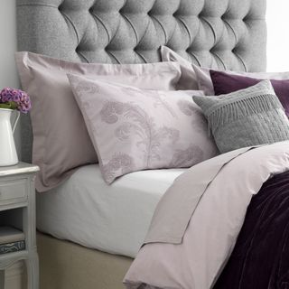 bedroom with grey headboard and cushions and throw