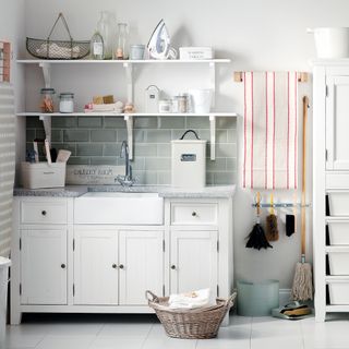 Laundry room with sage green metro tiled splash back, open shelving and selection of brushes