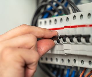 Close up of a person's hand operating a consumer unit