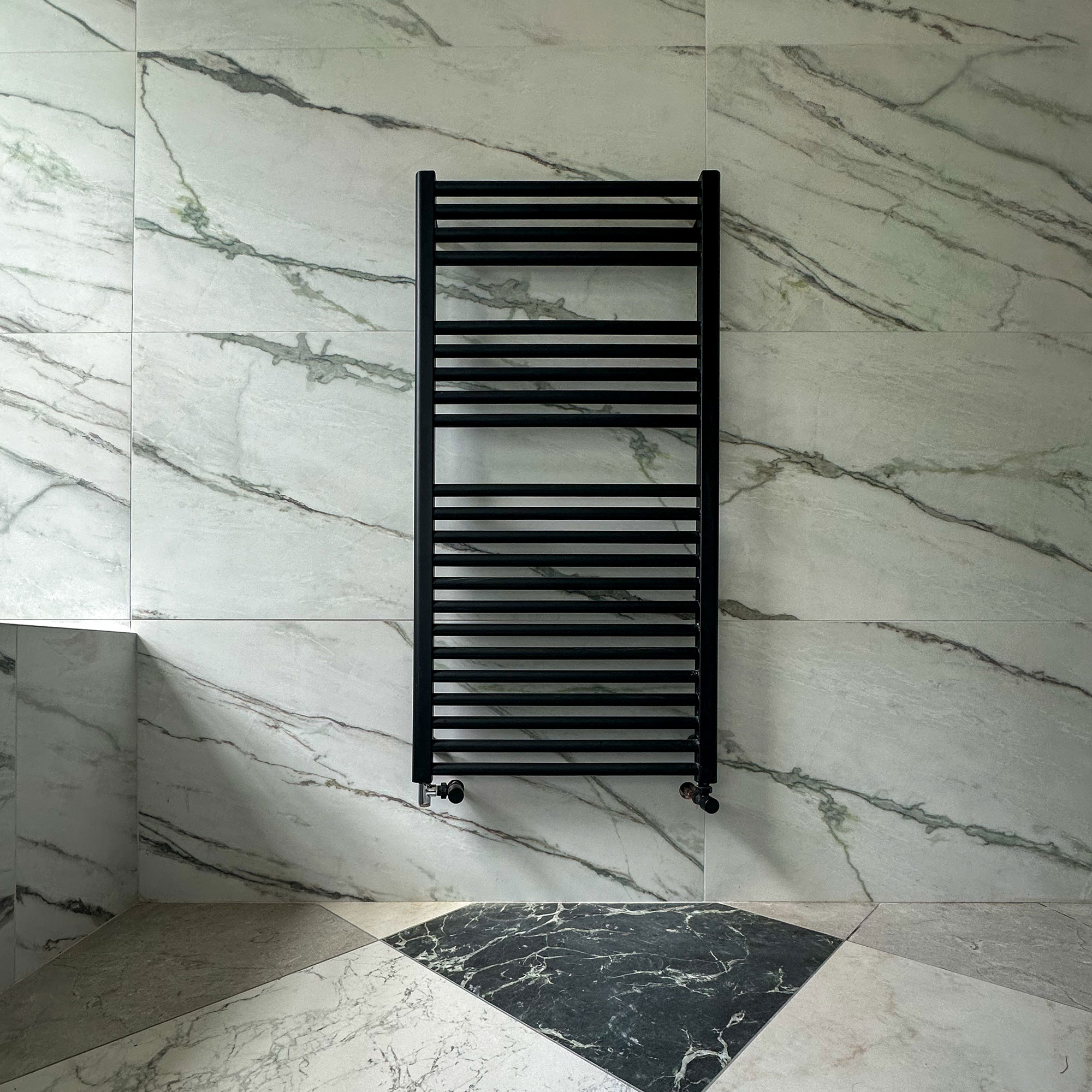 Black towel rail on tiled bathroom wall