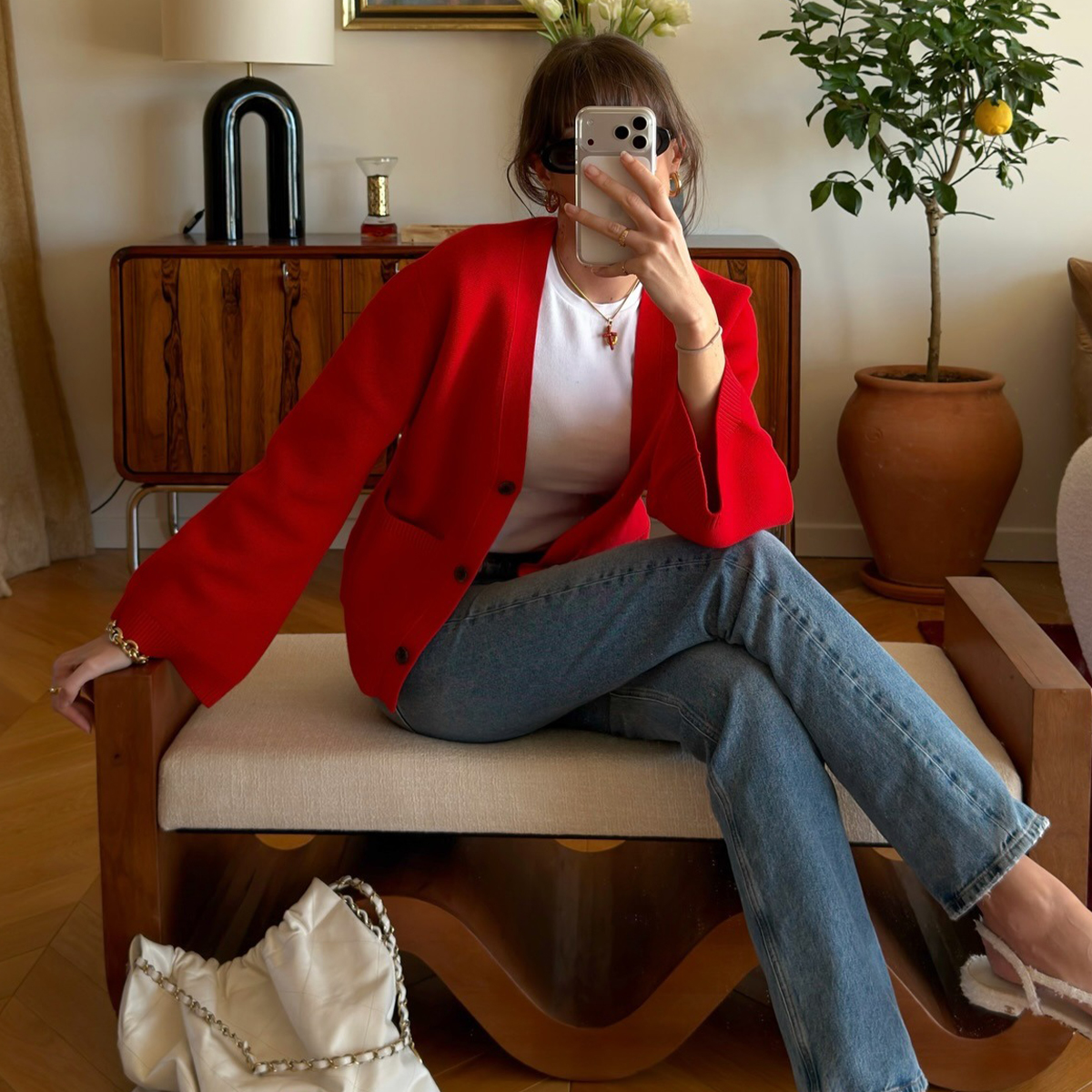 @juliesfi wearing a red cardigan, white crewneck, blue jeans, Chanel bag, and cap-toe slingback heels