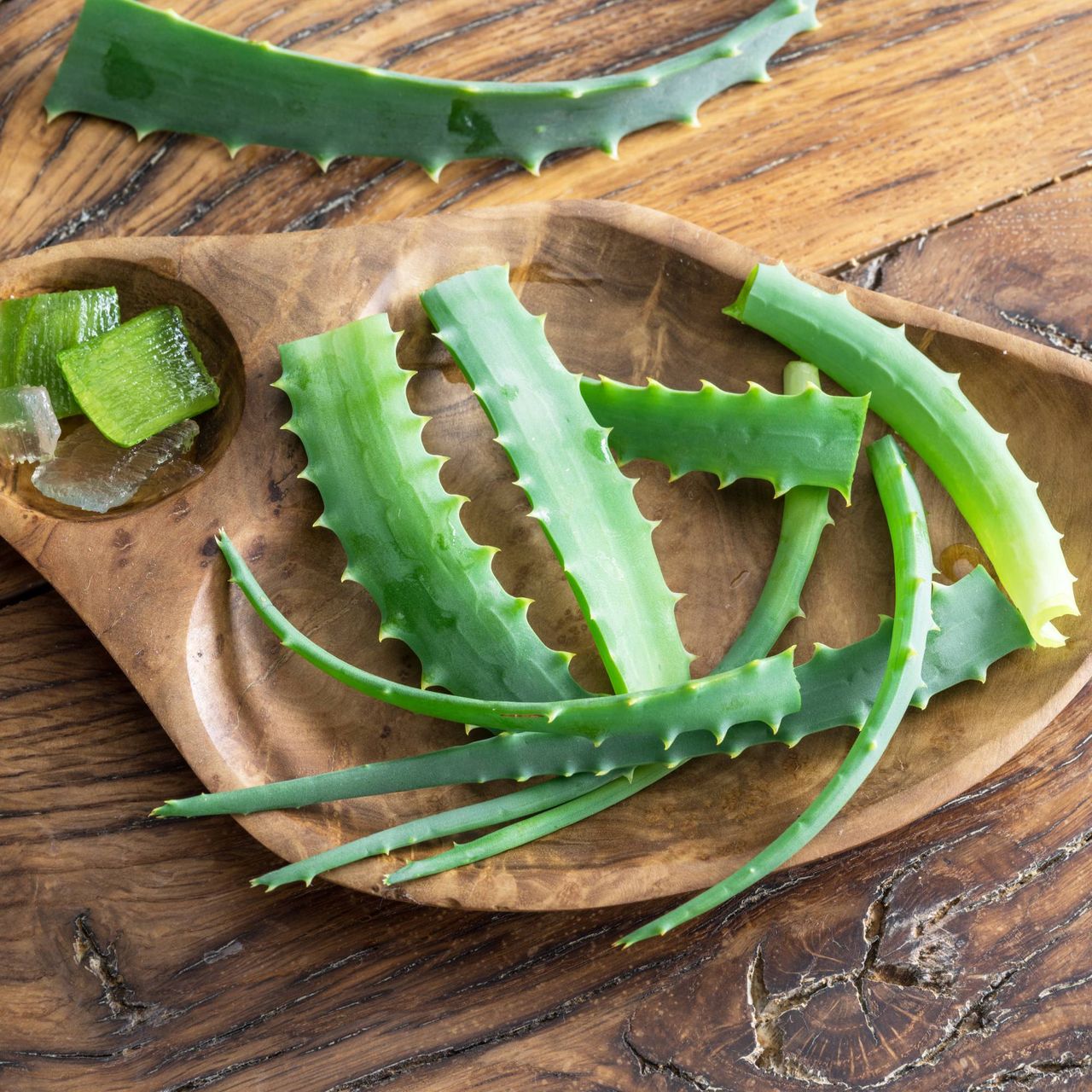 Slices of aloe leaves on a wooden plate with cubes of gel
