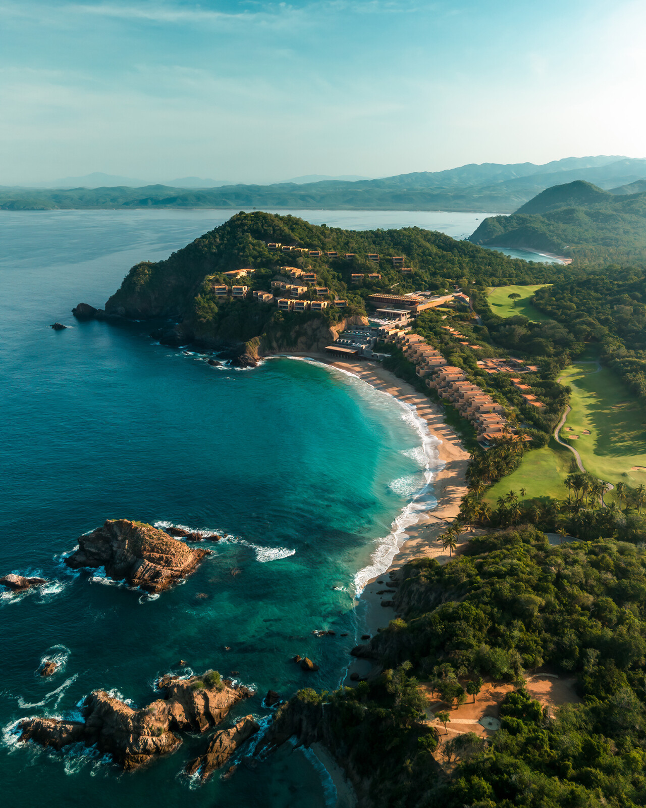 areal view of the four seasons tamarindo featuring the resort on the coastline of the pacific ocean with the golf course and jungle behind the structures