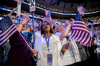 Delegates wearing white wave US flags during the Democratic National Convention (DNC) at the United Center in Chicago, Illinois, US, on Thursday, Aug. 22, 2024.