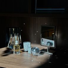 Photo of a candle, mirror, disco ball, and fragrance on a shelf