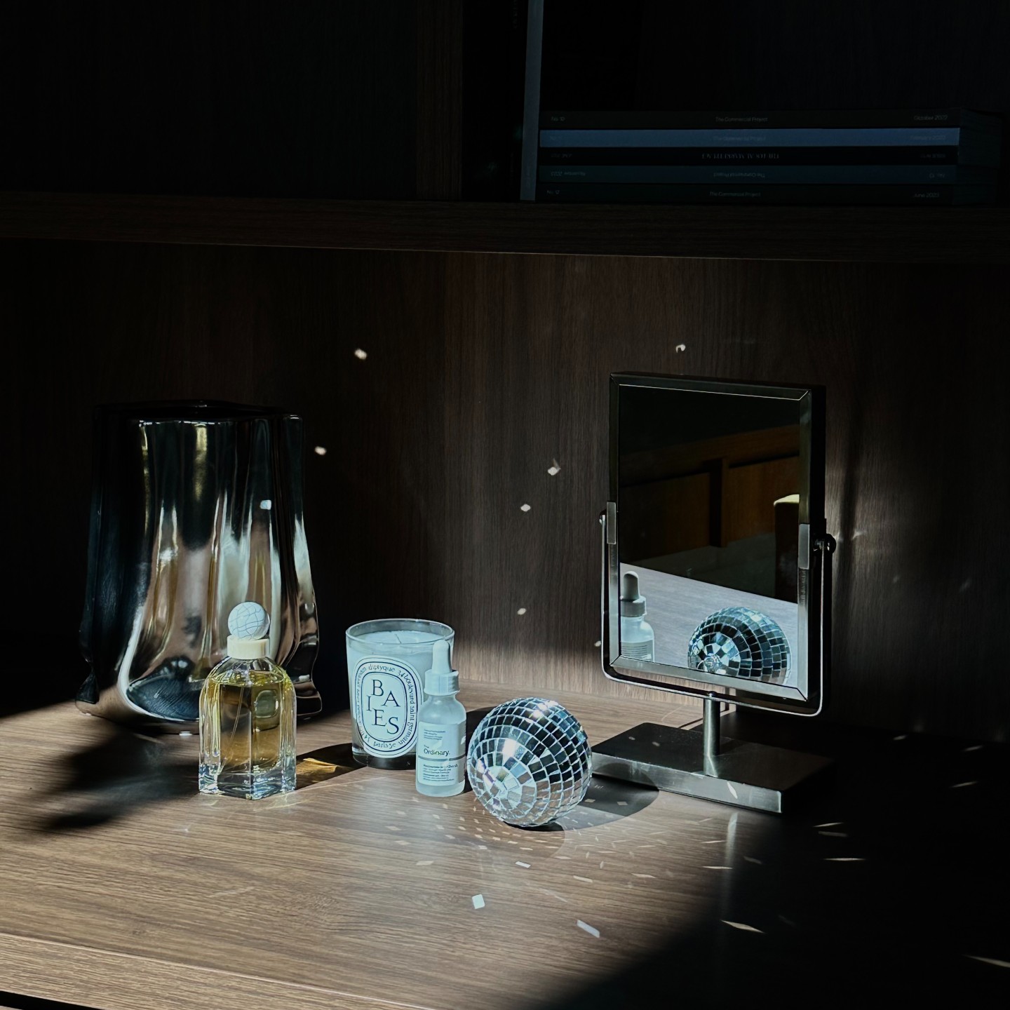 Photo of a candle, mirror, disco ball, and fragrance on a shelf
