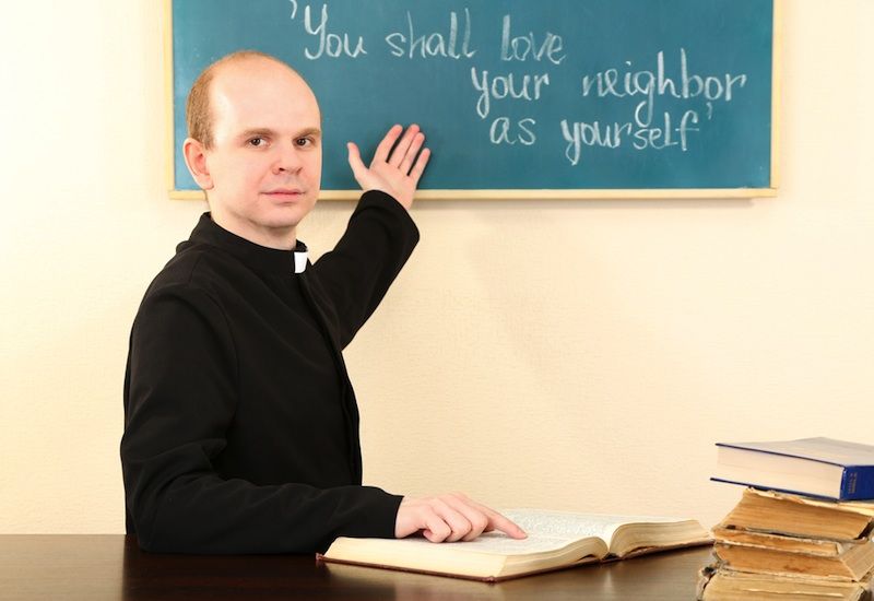 priest teaching sunday school at chalkboard