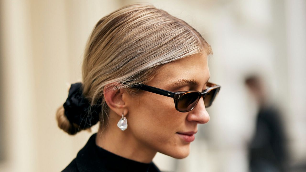 blonde woman wearing her hair in a low bun, wearing sunglasses and a black outfit