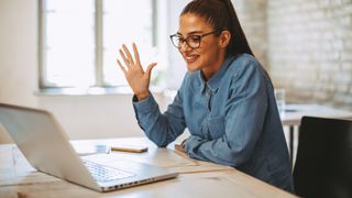 Woman waving on a video call using her laptop