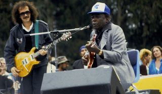 Carlos Santana (left) and John Lee Hooker perform in Golden Gate Park in San Francisco, California on June 23, 1985