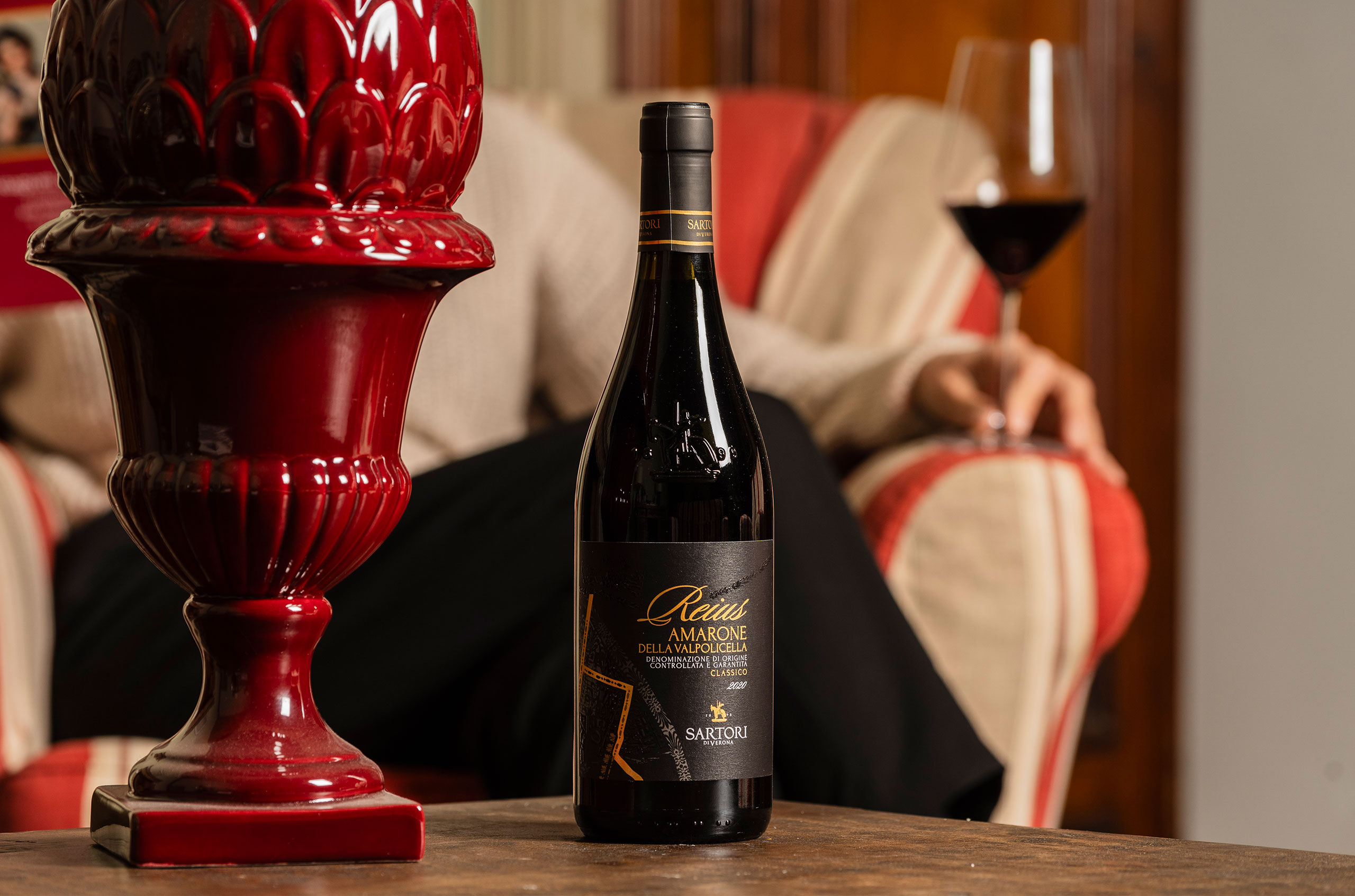 Bottle of wine and a person sat with a wine glass.