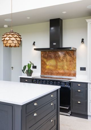 white kitchen with black cabinetry and a bold copper backsplash above the stove