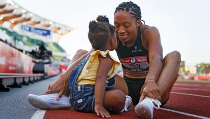 Runner Allyson Felix sits on the track with her baby daughter