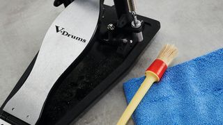 Paintbrush being used to clean a bass drum pedal