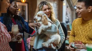 a smiling woman holds a puppy among a small gathering of her friends