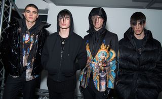 Four models in a line in dark clothing posing