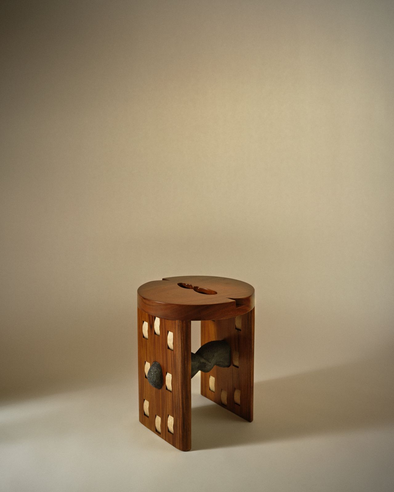 A beautifully conceived wooden stool features multiple inserts in pale and black wood, as well as incisions making the design geometrically striking.