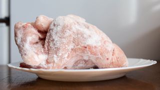A whole chicken defrosting on a plate