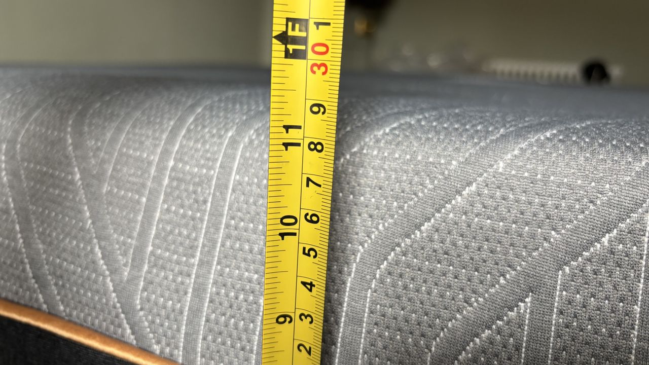 A measuring tape measures the height of a newly unboxed EGOHOME Black 12" Mattress.