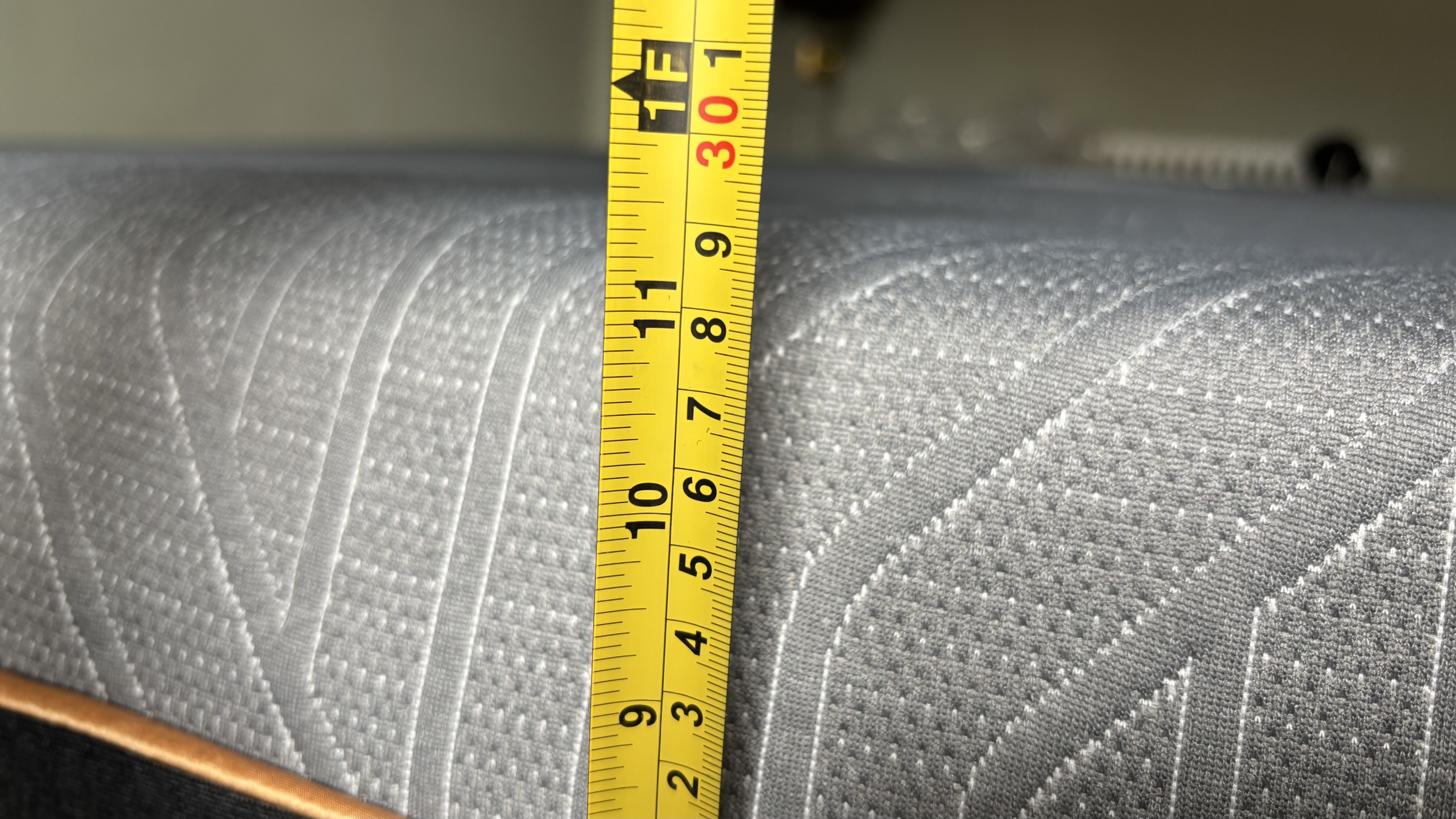 A measuring tape measures the height of a newly unboxed EGOHOME Black 12" Mattress.