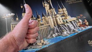 A hand giving a thumbs up in front of the Hogwarts Castle and Grounds Lego set box
