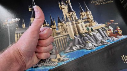 A hand giving a thumbs up in front of the Hogwarts Castle and Grounds Lego set box
