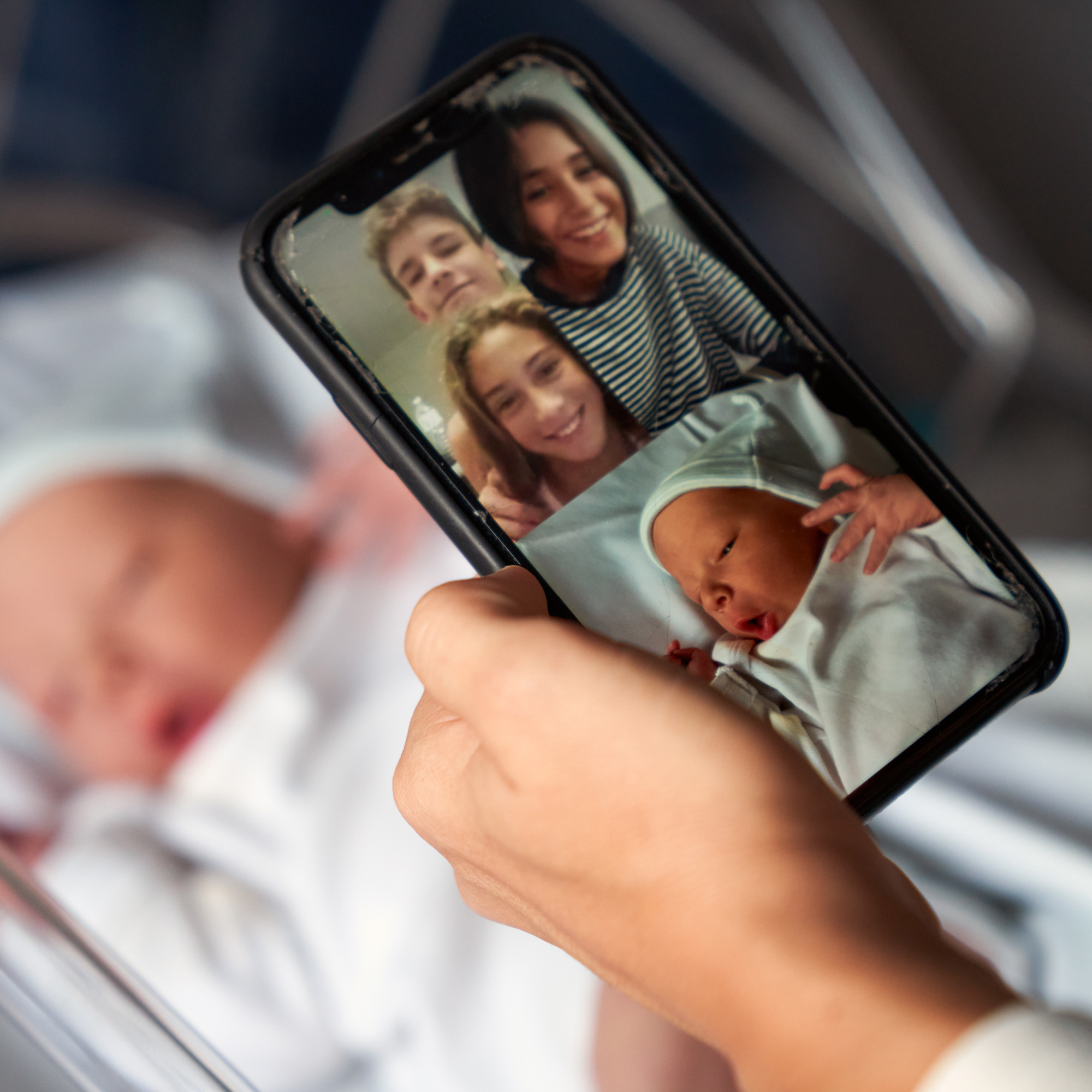 newborn baby on a smartphone video call with family